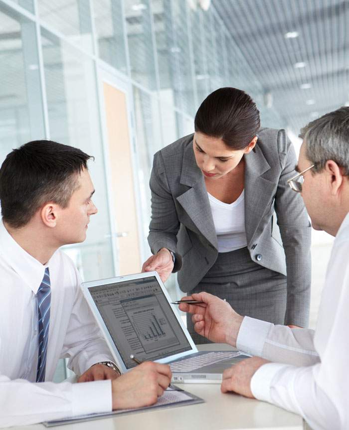 Three team members in discussion around a laptop computer